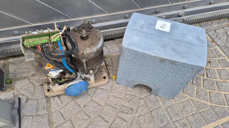 Motore di un cancello scorrevole aperto per la riparazione, con morsettiera e cablaggi a vista